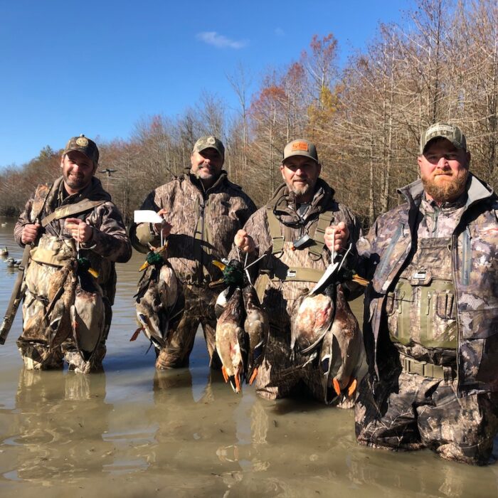 hunters in water holding ducks